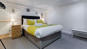 A modern bedroom with a bed, bedside tables, a bench, and a wall-mounted light fixture. - 1 Bed Home • Parking • Great for Contractors (Gorseinon)