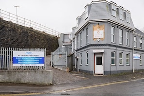 A grey building with a sign for KG Inspired Property, offering short stay accommodation, property maintenance, and property management.