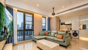 A modern living room with a sectional sofa, a marble coffee table, a large TV, and a city view. - Anara Aparthotel Chengdu Chunxi Road (Chengdu)