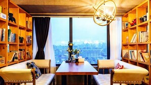 A room with a city view, a wooden bookshelf, a table with a vase, and two cushioned seating areas. - Anara Aparthotel Chengdu Chunxi Road (Chengdu)