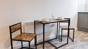 A small dining area with two wooden chairs, a table, and a glass of wine. - Contractor Base • Kitchen • Parking Included (Plasmarl)