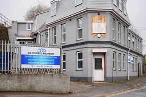 A multi-story building with a sign for KG Inspired Property, offering short stay accommodation, property maintenance, and management.