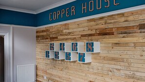 A room with a wooden wall, a sign reading 'COPPER HOUSE,' and numbered storage boxes. - Contractor Base • Kitchen • Parking Included (Swansea)