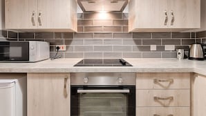 Een keuken met houten kastjes, een magnetron, een fornuis en een oven.