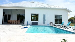 Et moderne hus med swimmingpool, overdækket terrasse og garage.