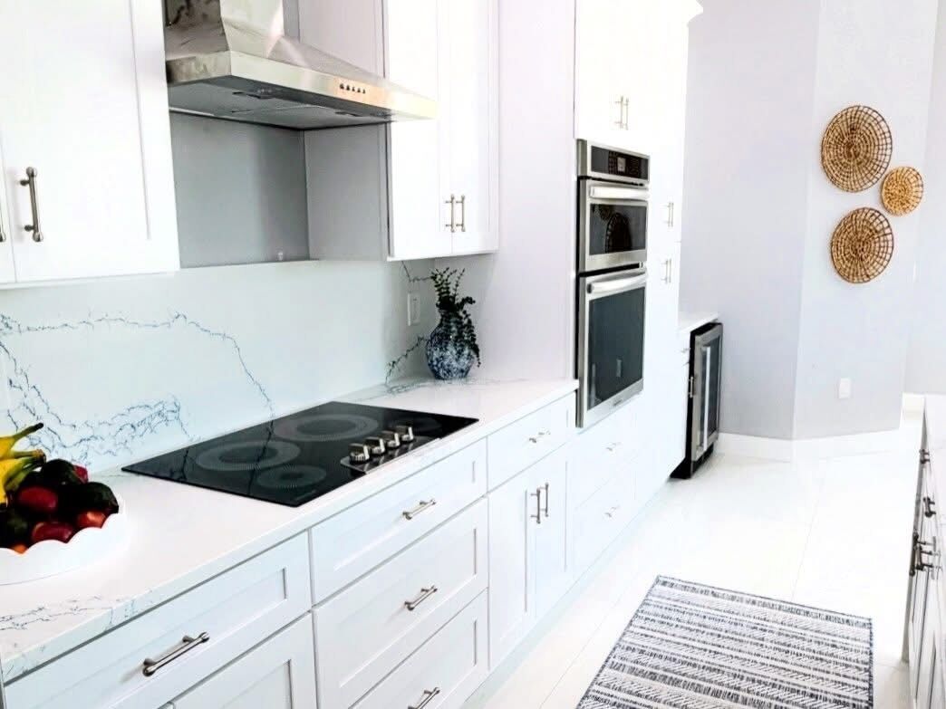 A modern kitchen with white cabinetry, a gas stove, an oven, and a built-in microwave.