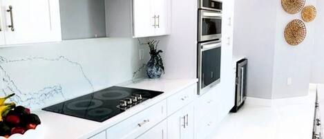 A modern kitchen with white cabinetry, a gas stove, an oven, and a built-in microwave.