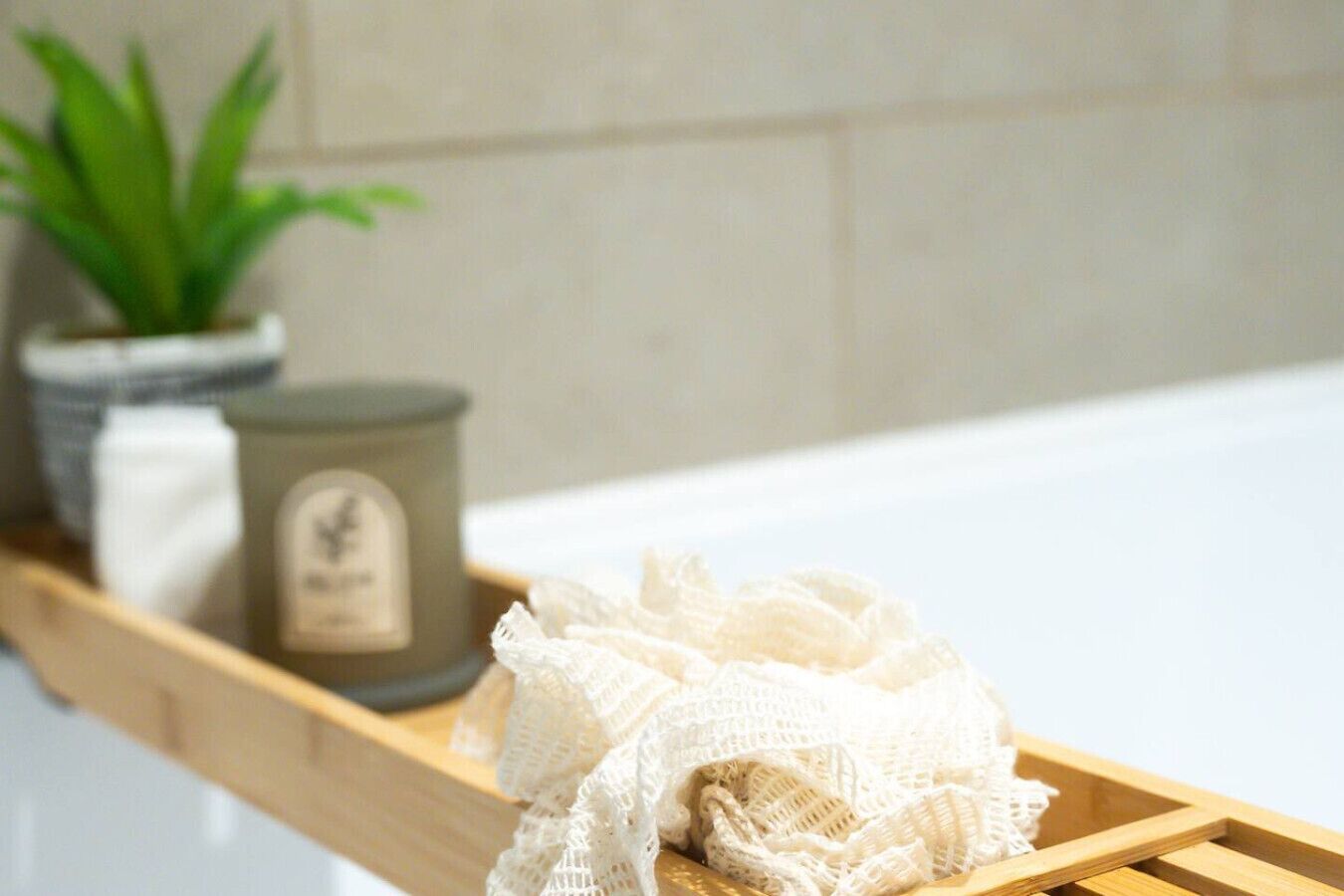 Een houten plank met een witte badjas, een kaars en een plant in pot.