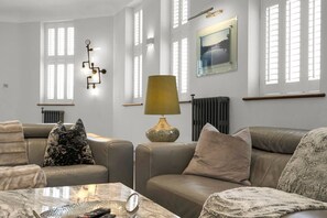 A living room with leather sofas, a marble coffee table, a lamp, and a painting on the wall. - Chic & Luxury - Central - Beach Access - Wind St (Swansea)