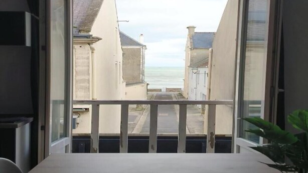 Un balcón con vista a una calle estrecha y al mar.