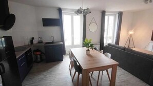 Una cocina moderna con una mesa y sillas de madera, horno empotrado y zona de comedor con sofá.