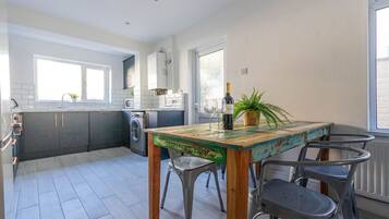 A modern kitchen with a dining area, a washing machine, and a large window.