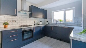 Una cocina moderna con armarios oscuros, baldosas blancas tipo metro, horno empotrado y ventana que proporciona luz natural.