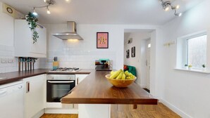 Una cucina moderna con mobili bianchi, un piano di lavoro in legno e un'isola centrale con una ciotola di frutta.