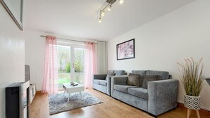 En moderne stue med en grå sofa, et hvidt sofabord og et fladskærms-tv.