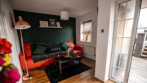 Ett vardagsrum med en röd soffa, ett svart soffbord och en vit lampa.