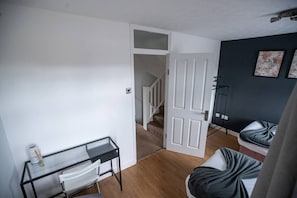 A room with a desk, chair, and a bed. There is a door leading to a staircase. - Beautiful Cardiff Wharf| Free Parking | WaterViews (Cardiff)