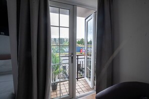 A room with a sliding glass door leading to a balcony with a tiled floor and potted plants. - Beautiful Cardiff Wharf| Free Parking | WaterViews (Cardiff)