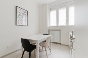 A room with a white table, two chairs, a radiator, and a window. - GuestHost - Comfortable and welcoming 45m2 apartment, perfect for four people, located on the ground floor of a building.The property is located near the M1 Gambara metro stop (5 minutes on foot) which will offer a quick connection to the most central an (Milan)