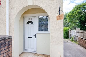 Eine weiße Tür mit der Nummer 1013, ein Rundbogen, ein Fenster mit Metallgitter und ein Schild mit der Aufschrift Carmarthen Road.