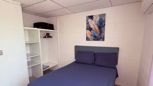 A bedroom with a bed, a white wardrobe, a shelf with clothes, and a painting on the wall. - Your Home way From Home (San Salvador)