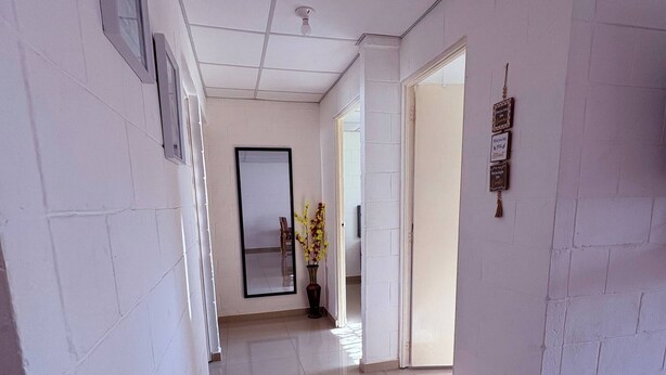 A hallway with white walls, a tiled floor, a large mirror, and a door leading to another room. - Your Home way From Home (San Salvador)