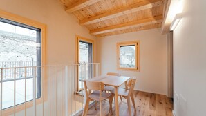 Une pièce avec un plafond en bois, une table entourée de chaises et de grandes fenêtres.