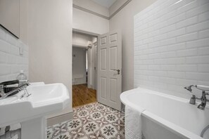 A bathroom with a white sink, a bathtub, and a door leading to another room. - 2 Streets from Centre | Free Parking | Fast WIFI (Cardiff)