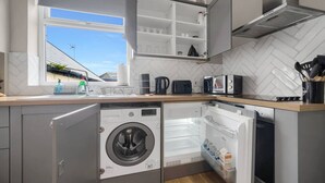 Una cucina compatta con lavatrice integrata, forno a microonde e lavastoviglie.