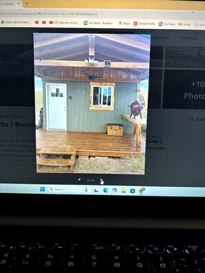 Eine Holzhütte mit Tür, Fenster und Grill vor der Tür.