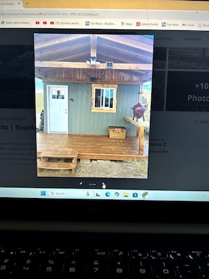 A wooden cabin with a door, window, and a barbecue grill outside.