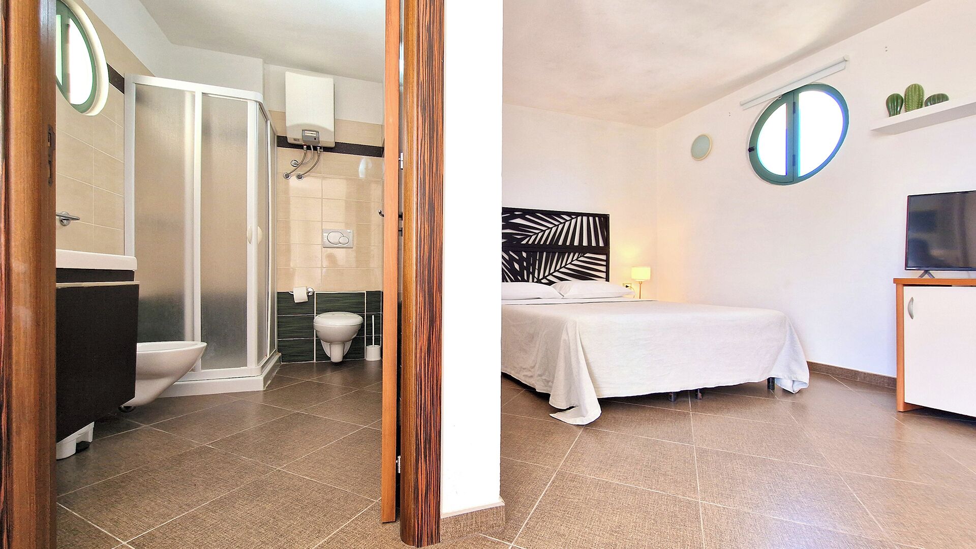 Une chambre d’hôtel équipée d’une douche, de toilettes, d’un lit, d’une table de chevet et d’un téléviseur.