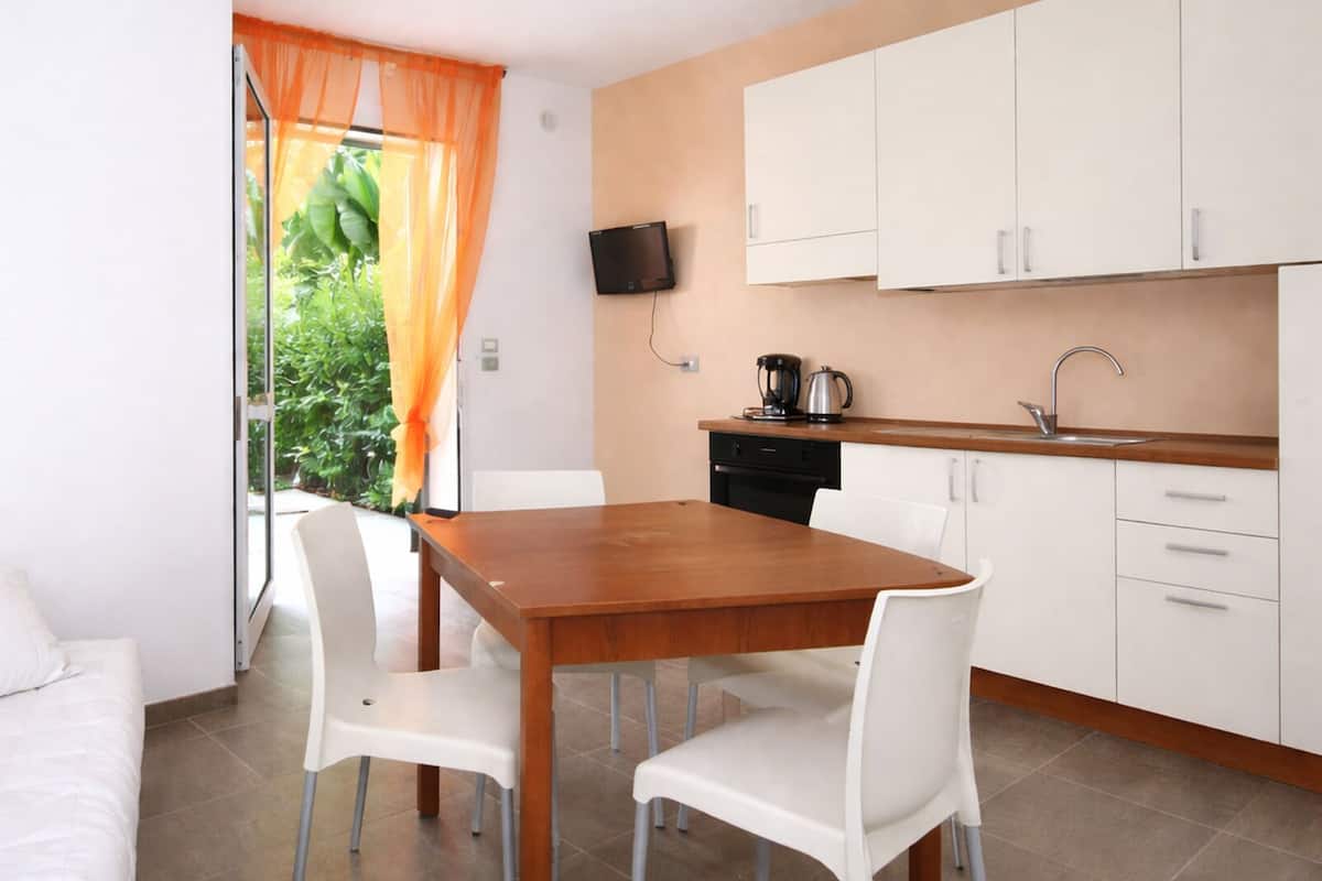 A modern kitchen with white cabinets, a wooden dining table, and white chairs.