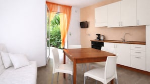 A modern kitchen with white cabinets, a wooden dining table, and white chairs.