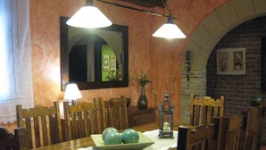 Un coin repas avec une table en bois, des chaises, un vase orné de branches et une lanterne posée sur la table.