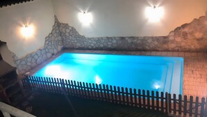 Une piscine avec des murs en pierre et une clôture en bois.