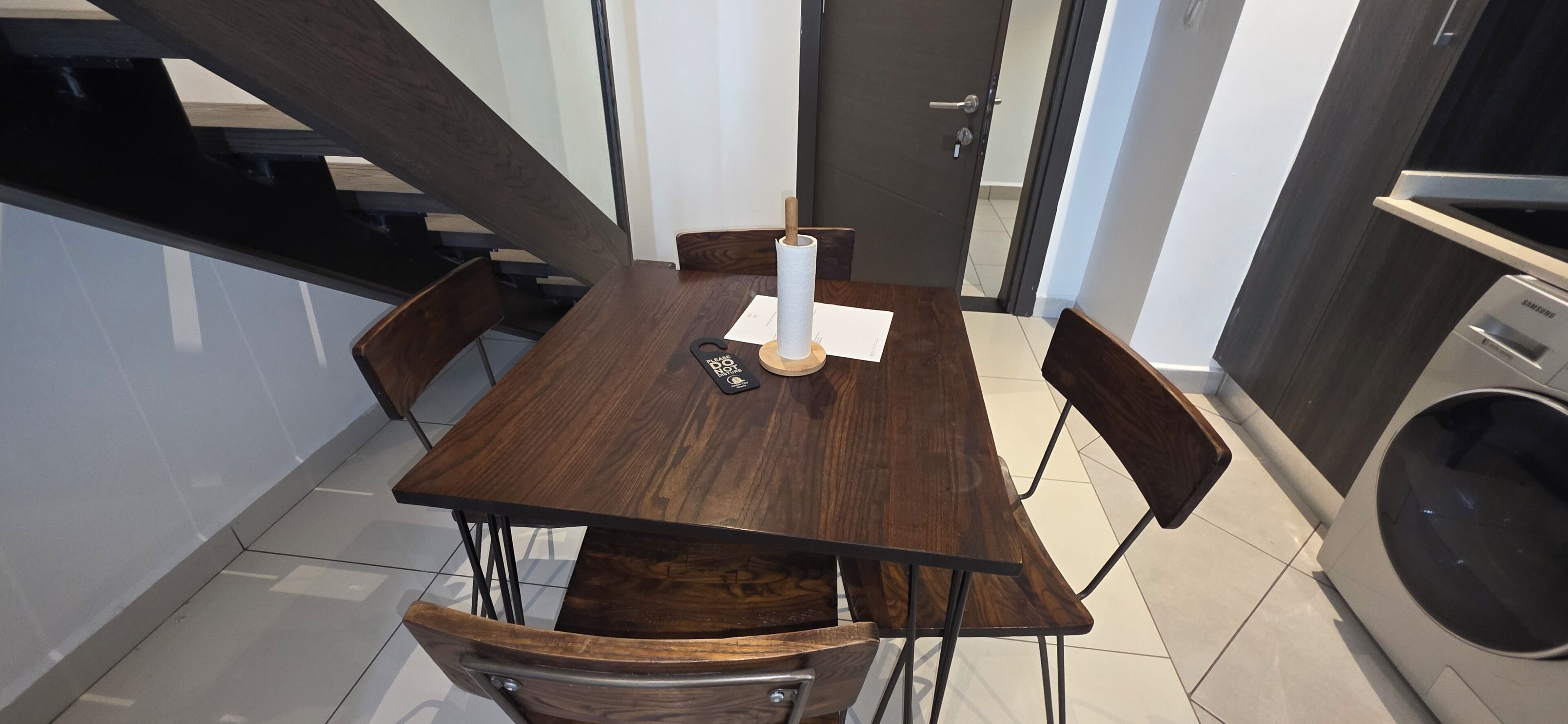 Una cocina moderna con una mesa de comedor de madera, sillas, una lavadora y una puerta.