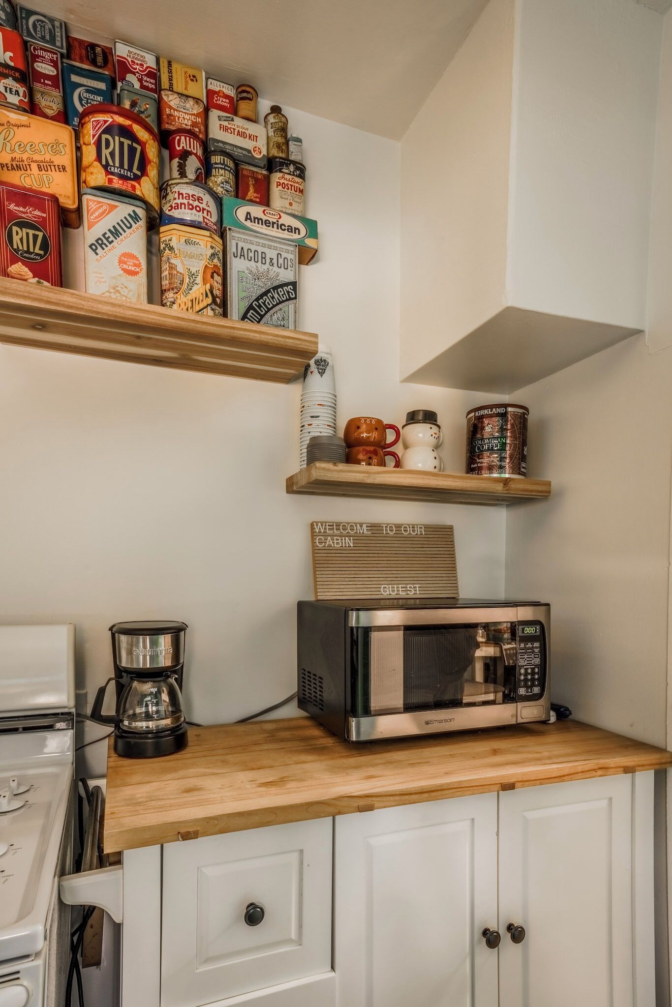 Une cuisine équipée d’une machine à café, d’un four à micro-ondes et d’étagères remplies de différents produits alimentaires.