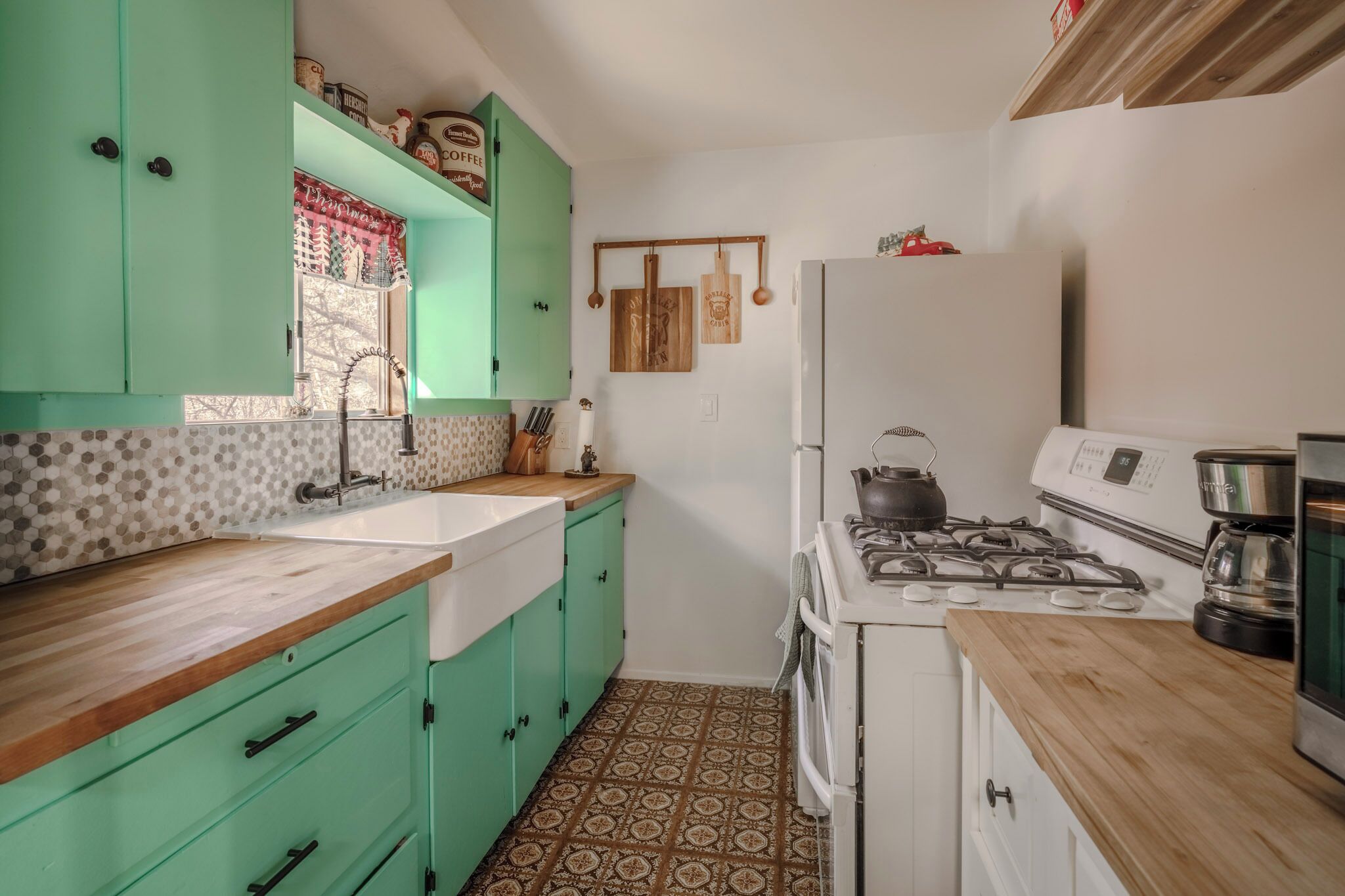 Una cocina con gabinetes verdes, una estufa blanca y un piso de baldosas estampadas.