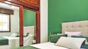 A bedroom with two beds, a green wall, and a wooden wardrobe. - Stylish Beachside Apartment | Ocean Views, 380m from Playa de Silgar, Sanxenxo (Sanxenxo)