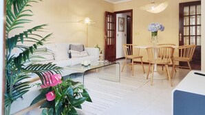 A living room with a sofa, coffee table, dining table with chairs, and a door leading to another room. - Stylish Beachside Apartment | Ocean Views, 380m from Playa de Silgar, Sanxenxo (Sanxenxo)