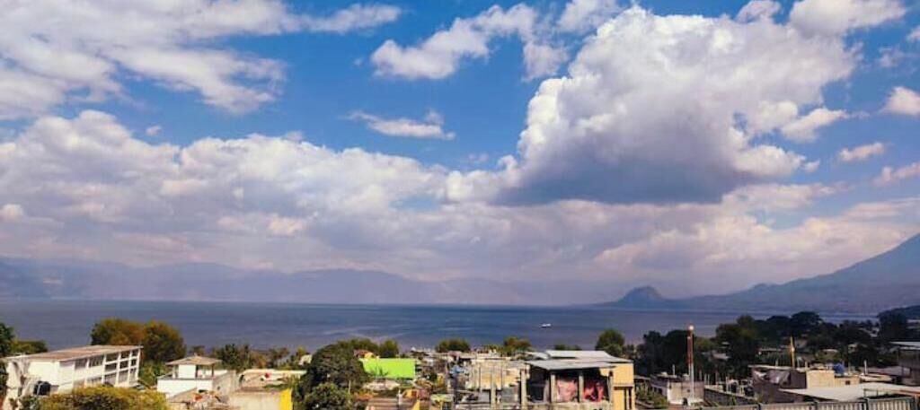 A coastal cityscape with buildings, a clear sky, and a distant mountain.