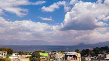 A coastal cityscape with buildings, a clear sky, and a distant mountain.