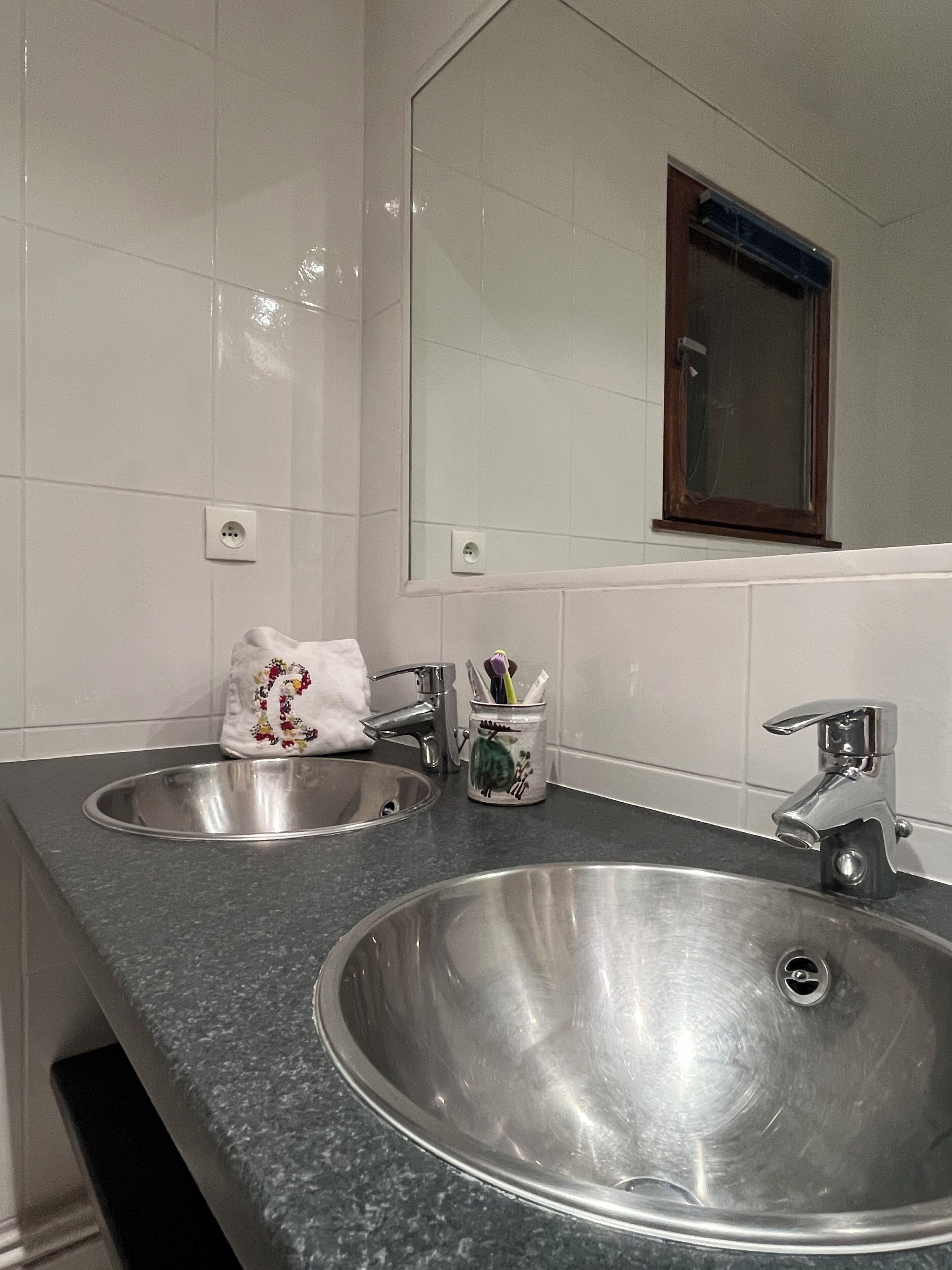 A bathroom with two sinks, a mirror, and a window.