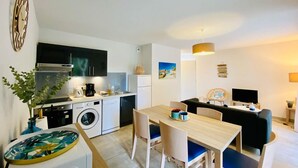 Ett kompakt bostadsutrymme med ett litet kök, en matplats och en sittgrupp.