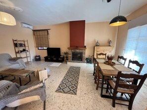 A living room with a fireplace, a dining area with wooden furniture, and a bookshelf.