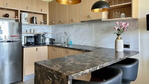 Una cocina moderna con armarios de madera, encimera de mármol e iluminación colgante.