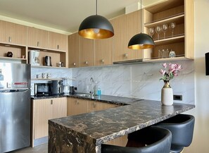A modern kitchen with wooden cabinets, a marble countertop, and pendant lighting. - Entire rental unit in Rawai, Thailand (Rawai)
