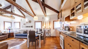 Amplia sala de estar con vigas de madera, una mesa de comedor y una cocina con armarios de madera y un microondas.