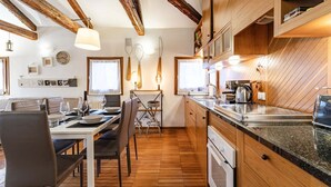 Una cocina con vigas de madera, un comedor con mesa y sillas, y vistas al exterior.